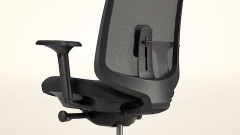 A Verus Chair with a black suspension back and a black seat and frame viewed at an angle with a pale yellow background.