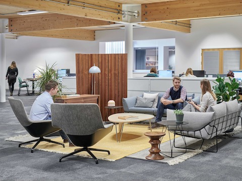 People meet in a casual work setting featuring Striad Chairs and Wireframe Sofa Group.