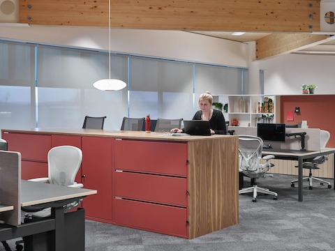 An employee works at a Meridian island while seated on a Setu Stool.
