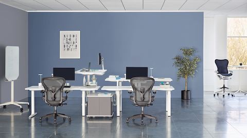 A collaboration area featuring white height-adjustable Atlas Office Landscape desks and black Aeron office chairs.