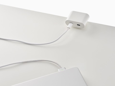 Ello Mini surface clamp USB-C power solution shown in white charging a laptop.