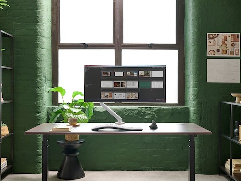 White Flo Single monitor arm viewed from the front in a working environment.