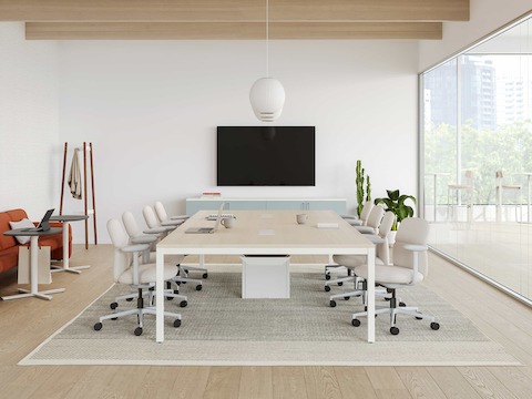 A glass-walled conference room with a Layout Studio meeting table and seating, along with a television for video conferencing and presentations.