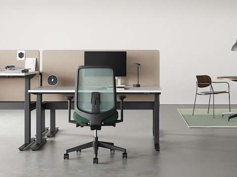 Four Nevi Sit-Stand Desks positioned back to back at seating and standing heights. A pair of Lino Chairs are alongside.