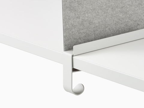 Close up image of a grey OE1 Boundary Screen bag hook attached to a white surface, viewed from an angle.