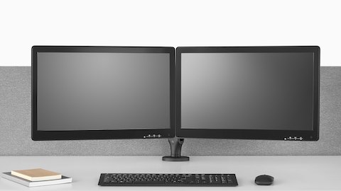 Two Ollin Monitor Arms, one connected to a Flo Power Hub, elevate a pair of monitors off the surface of a sit-to-stand table.