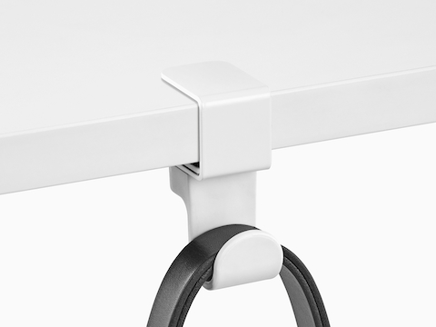 A black strap loops over a Ubi Bag Hook clamped onto a work surface.