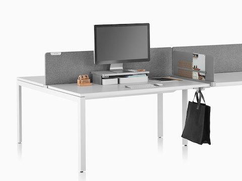 A work surface equipped with Ubi Work Tools, including a gray monitor platform shelf, slim screen, and bag hook.