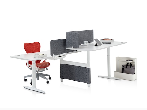 A workspace featuring a red Mirra 2 office chair, two height-adjustable desks, and various Ubi Work Tools to aid organisation.