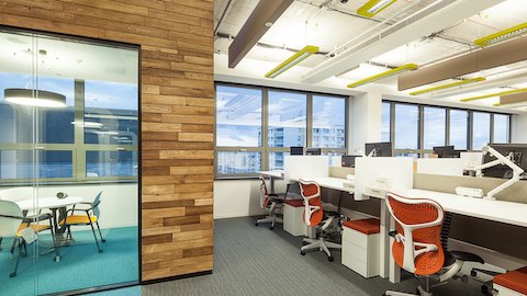 Mirra 2 Chairs at height-adjustable desks next to a small meeting room with Keyn Chairs.