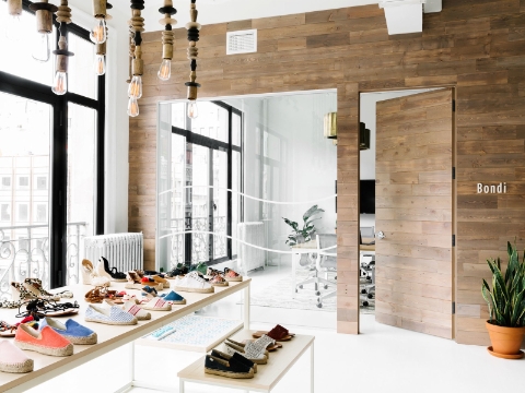 Rows of shoes sit on tables outside of an office entrance. 