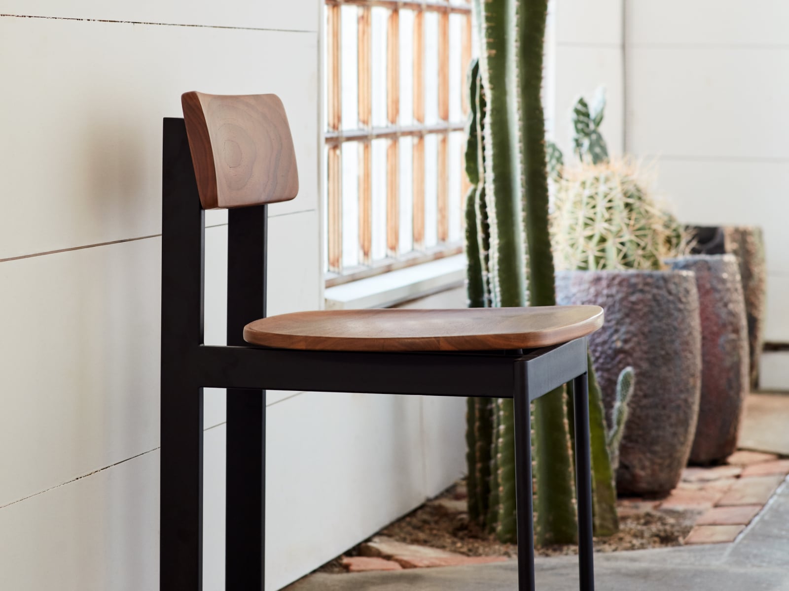 A close-up of a Betwixt Chair sitting against a wall.