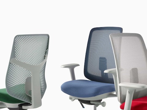 A close-up view of a Verus Chair with a green Triflex back, a Verus Chair with a blue seat and suspension back, and a Verus Chair with a grey suspension back with a red seat.