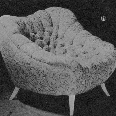 An archival black and white photo of the Rohde Easy Chair, an upholstered cushy lounge chair with tapered wood legs and tufting in a diamond pattern.