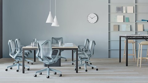 Several low-back Cosm Chairs in light blue glacier finish surround a Layout Studio conference table in an airy open office space. Select to search for a Herman Miller dealer.