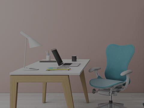 A laptop computer, coffee cup, and other elements of work sit on a white rectangular desk served by a blue Mirra 2 office chair.