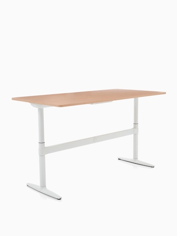 An adjustable Atlas Office Landscape desk with a woodgrain top, positioned at standing height and viewed at an angle.